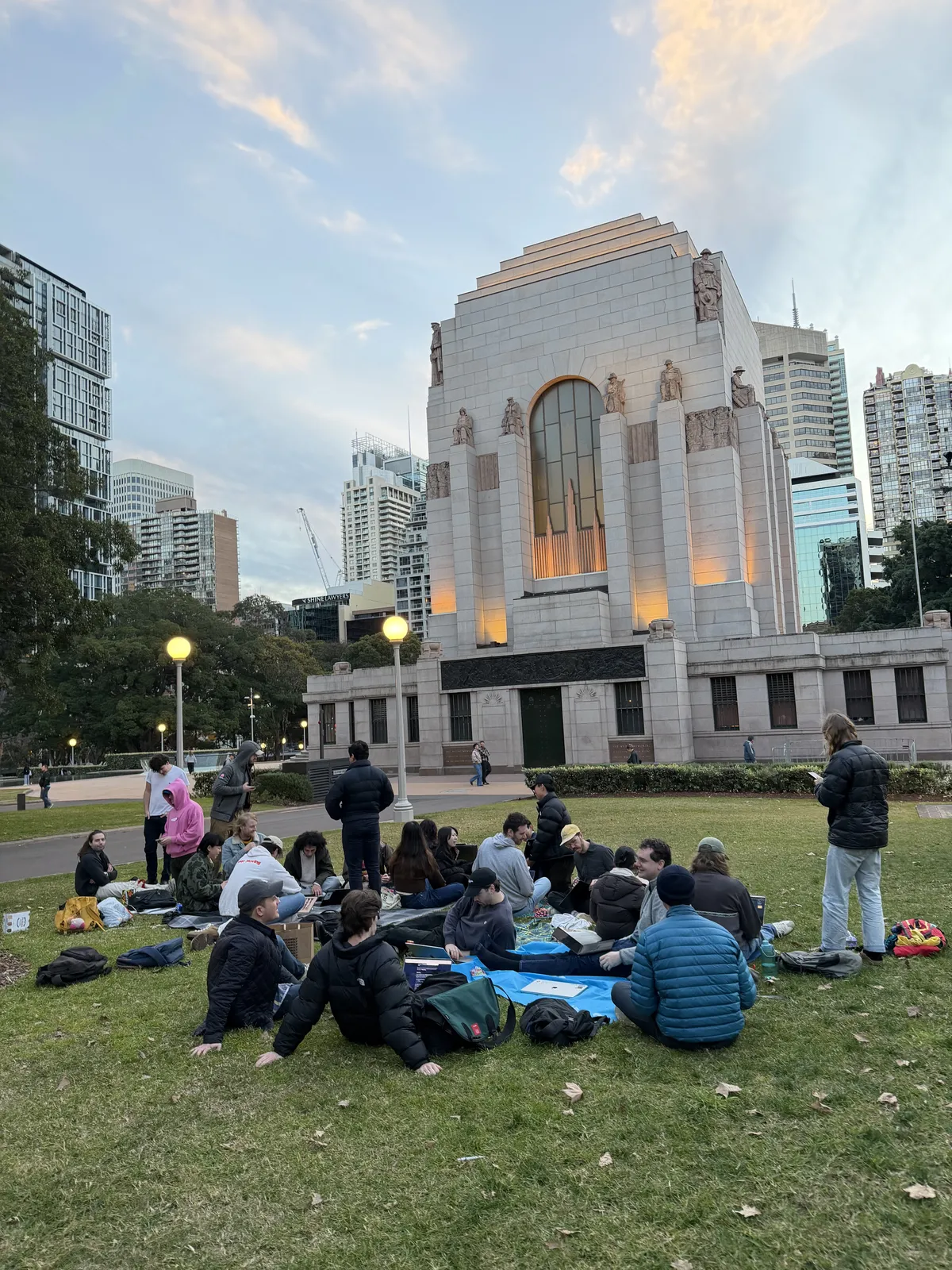 Group sitting by the Anzac Memorial at dusk
