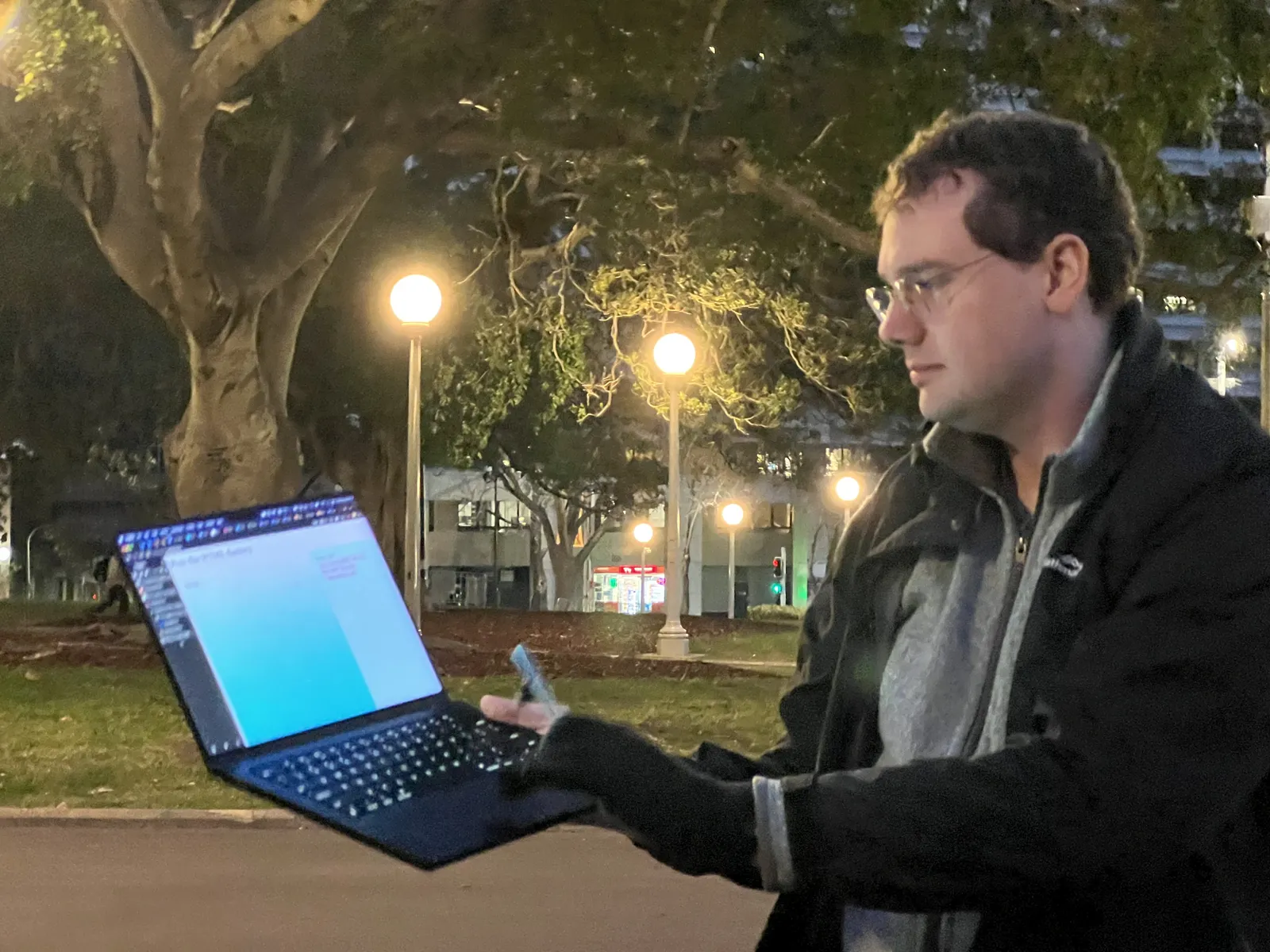 Standing with a laptop among open machines on the grass